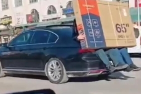 Yeni alınan televizyonu otomobilin bagajına oturan 2 kişi taşıdı
