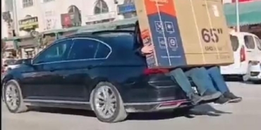Yeni alınan televizyonu otomobilin bagajına oturan 2 kişi taşıdı