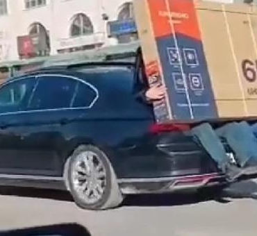 Yeni alınan televizyonu otomobilin bagajına oturan 2 kişi taşıdı