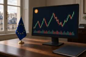Paris çatılarına bakan bir kurum ofisinde, masasında AB bayrağı duran monitörde yeşil ve kırmızı mum grafiği ile hacim çubukları ve Bitcoin logosu, MiCA revizyonu için temsili görsel