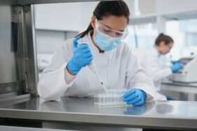 İngiltere’de bir biyogüvenlik laboratuvarında maske, gözlük ve eldiven takan araştırmacının güvenlik kabini içinde pipetle numune tüplerine sıvı aktardığı an, İngiltere yapay zeka paketindeki AI Biosecurity Lab için temsili görsel