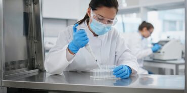 İngiltere’de bir biyogüvenlik laboratuvarında maske, gözlük ve eldiven takan araştırmacının güvenlik kabini içinde pipetle numune tüplerine sıvı aktardığı an, İngiltere yapay zeka paketindeki AI Biosecurity Lab için temsili görsel