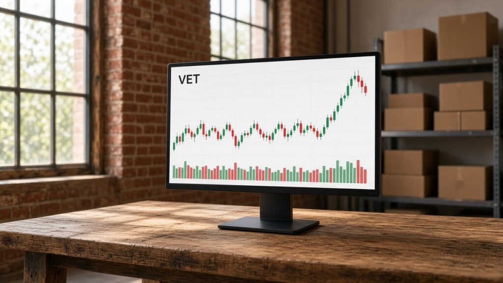 Tuğla duvarlı depo ofisinde ahşap masadaki açık temalı monitörde VET mum grafiği ve hacim çubukları, VeChain için temsili görsel